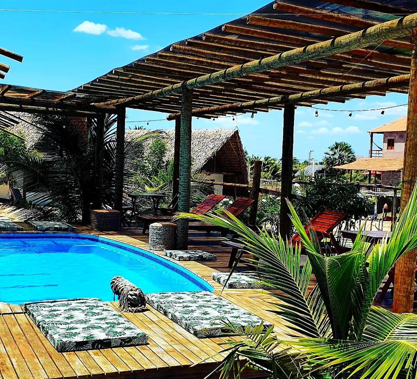 a swimming pool with two lounge chairs and a pergola at Chalé Sienna Ar condicionado Pousada 35knots Brasil in Luis Correia