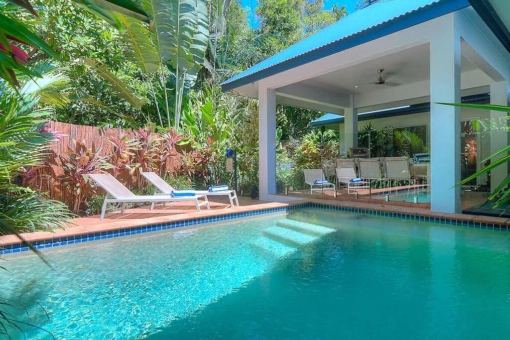 a swimming pool with chairs and a house at Beauty tiny Walk To Sea in Port Douglas
