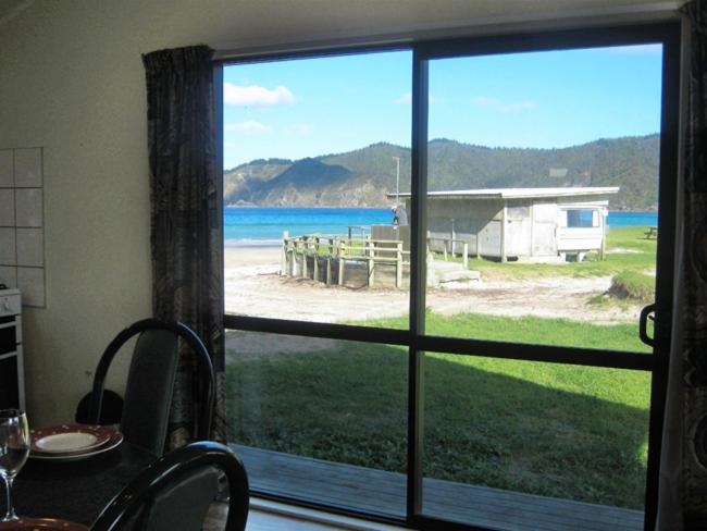 una ventana de una casa con vistas a la playa en Matauri Bay Holiday Park en Matauri Bay