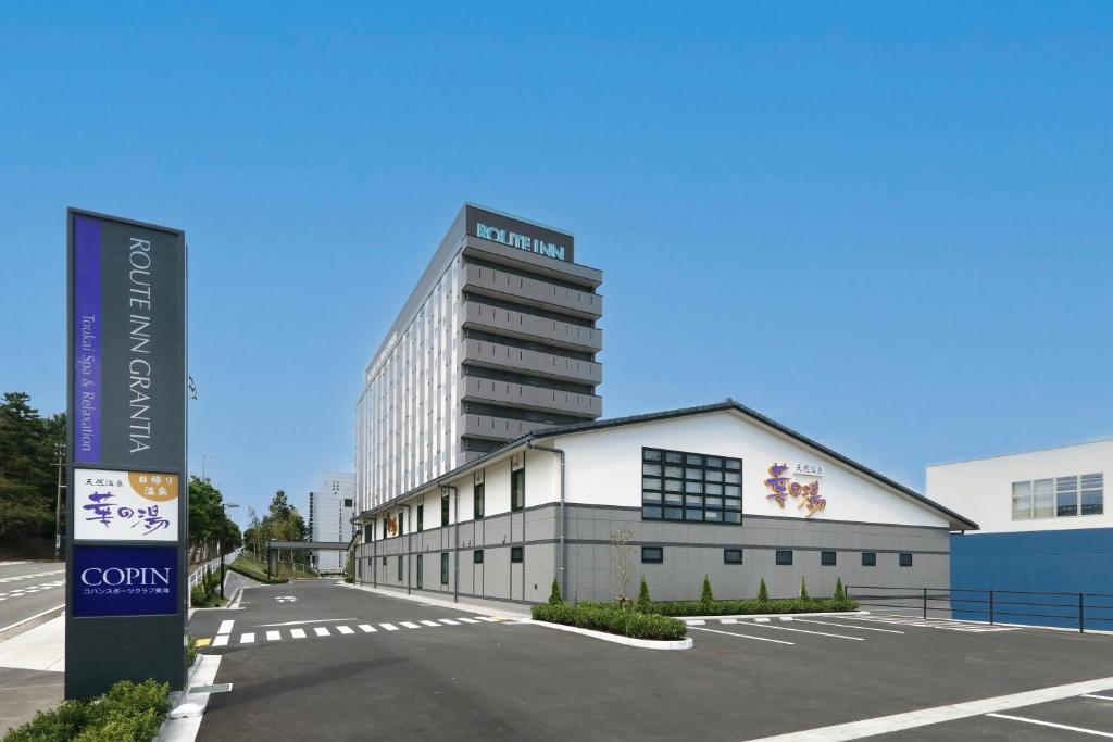 un edificio in un parcheggio con un edificio alto di Route Inn Grantia Tokai Spa&Relaxation a Tokai