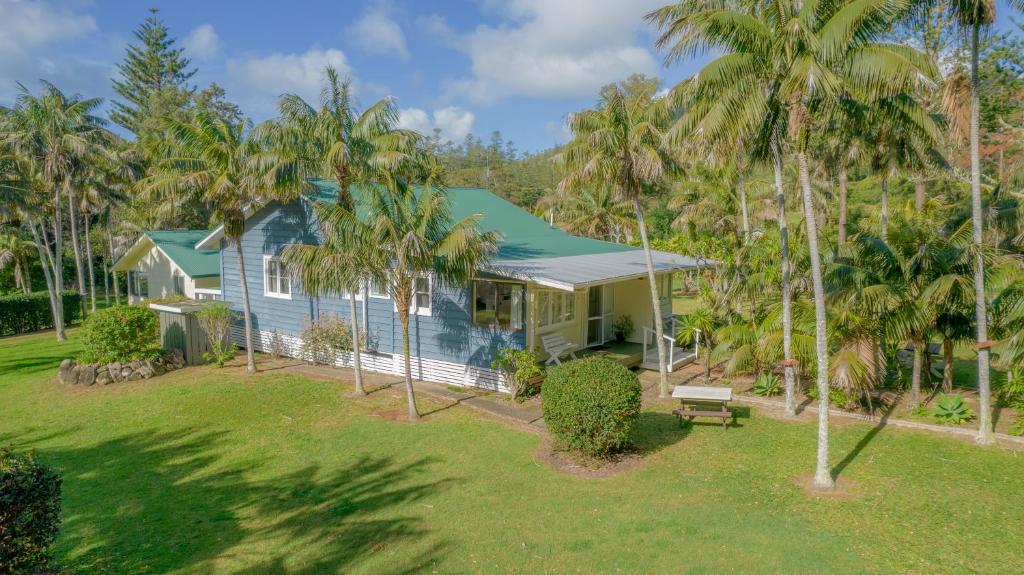 a blue house with palm trees in front of it at Anson Bay Lodge in Burnt Pine