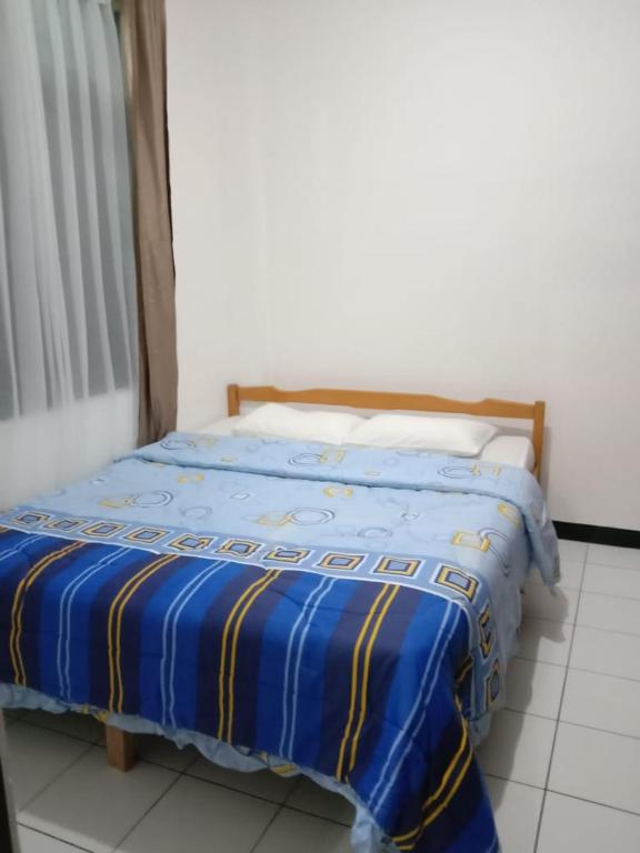 ein Bett mit einer blauen und gelben Bettdecke in einem Zimmer in der Unterkunft KEY HOMESTAY in Pasakon 1
