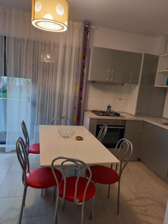 eine Küche mit einem weißen Tisch und roten Stühlen in der Unterkunft Casandra in Mamaia Nord – Năvodari