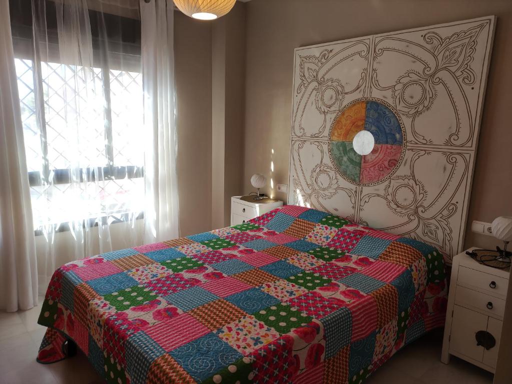 a bedroom with a bed with a colorful quilt on it at Apartamento Costa de la Luz in Rota