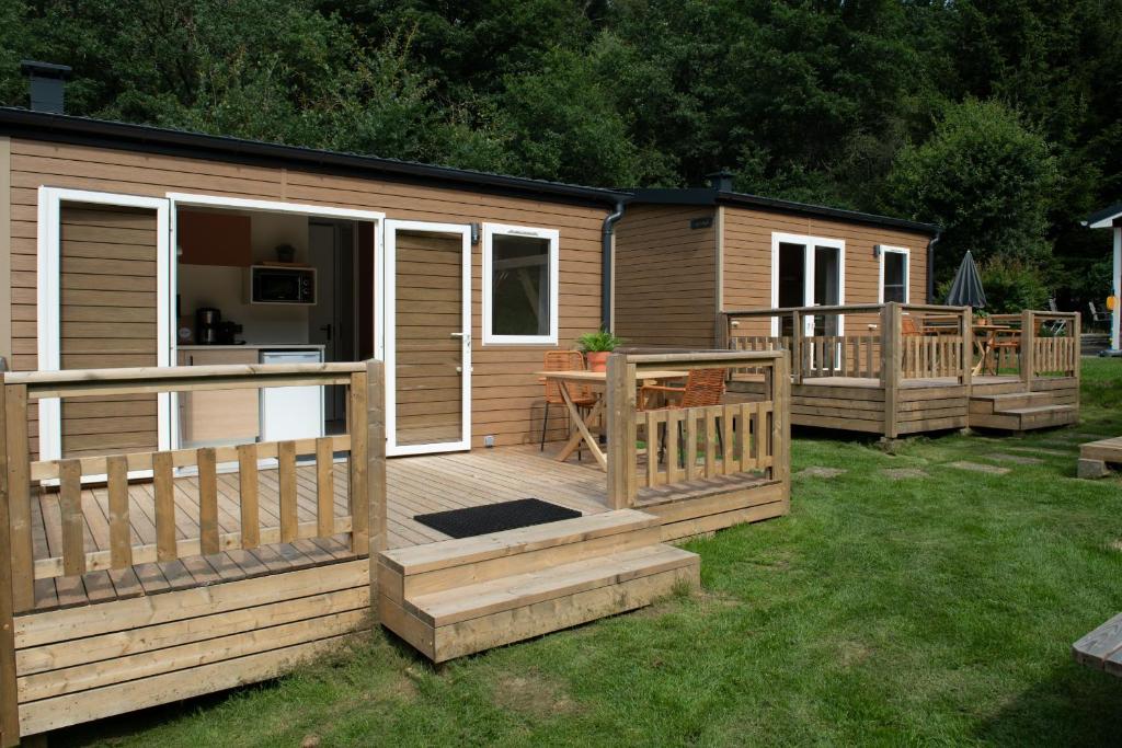 een grote houten hut met een veranda en een terras bij Tiny House in Enscherange