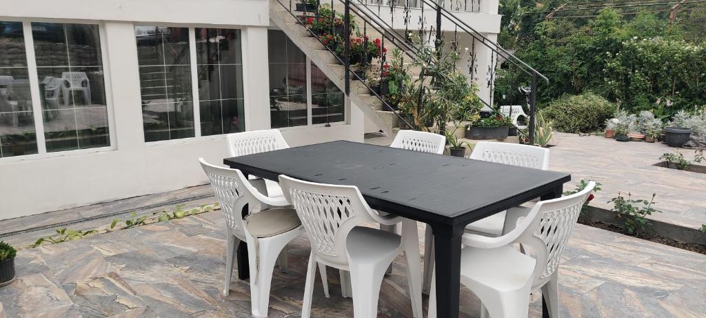 a black table and white chairs on a patio at Casa Narcisa in Băile Herculane