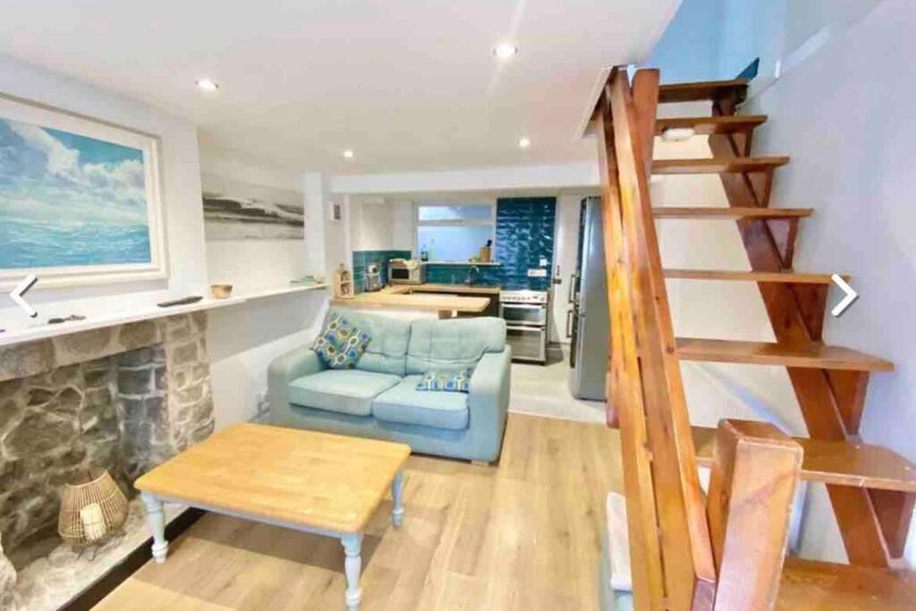 a living room with a blue couch and a fireplace at Traditional 2-bedroom Cornish cottage in Newlyn in Newlyn