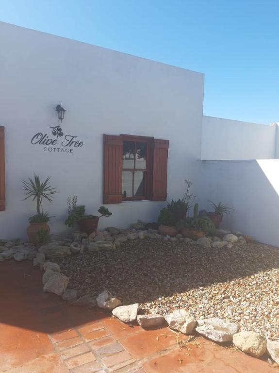 a house with a garden in front of a building at Olive Tree Cottage in Paternoster
