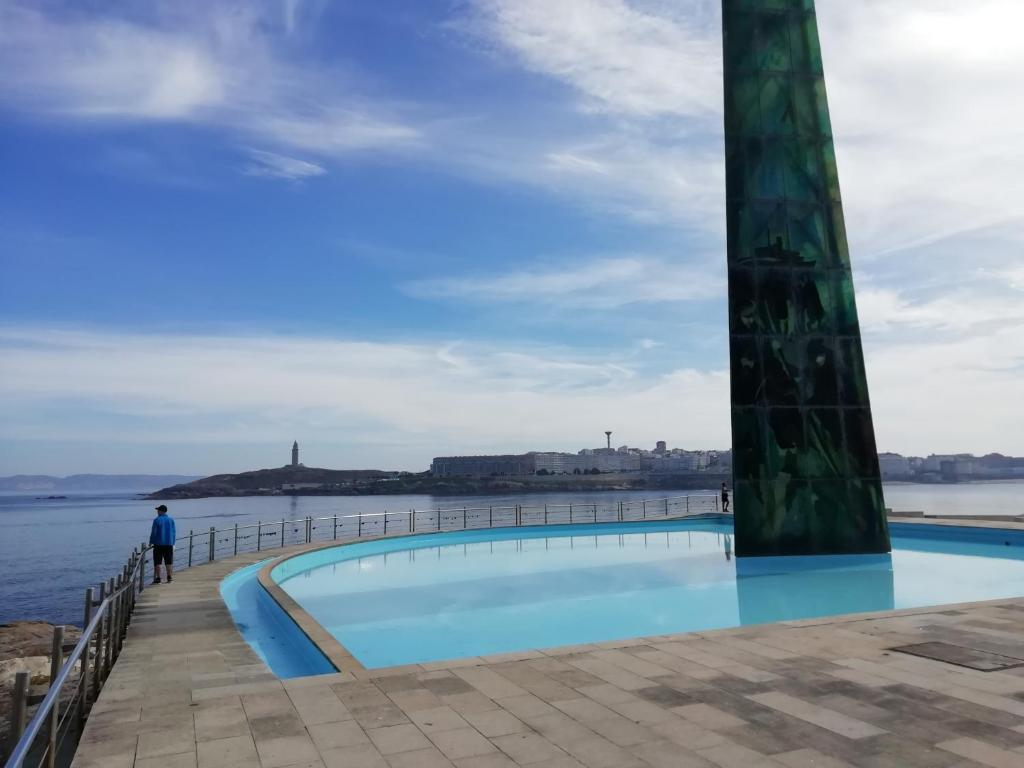 un hombre de pie junto a una piscina al lado del agua en Millennium, en A Coruña