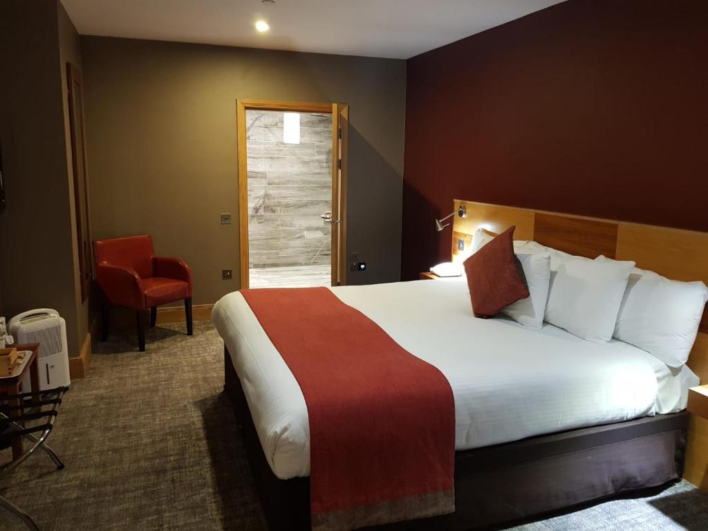 a hotel room with a large bed and a chair at The Inn on Loch Lomond in Luss