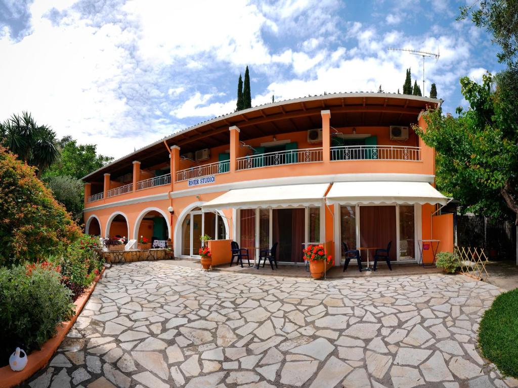 - un grand bâtiment orange avec une terrasse en face dans l'établissement River Studios, à Paleokastritsa