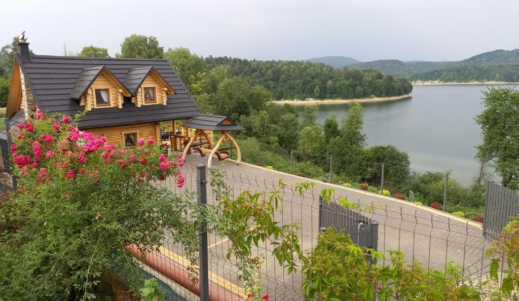 a house on the side of a wall next to a lake at Domek Nad River San in Olchowiec