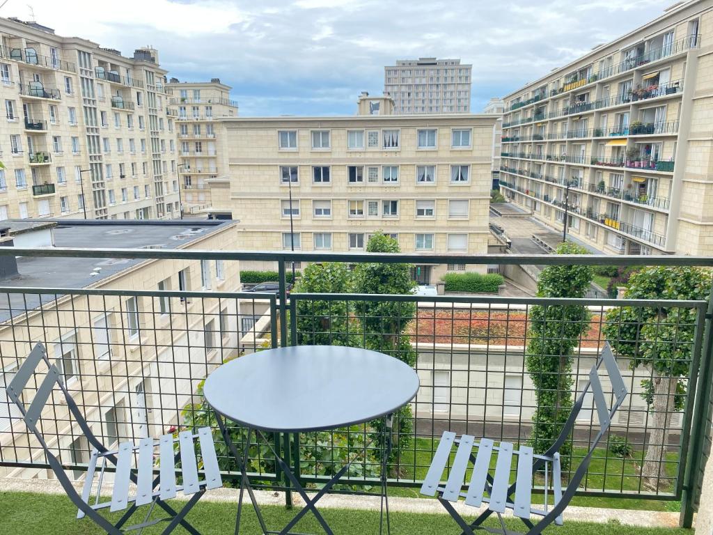 einen Tisch und zwei Stühle auf einem Balkon mit Gebäuden in der Unterkunft Vivez Le Centre ville à la Plage - Balcon in Le Havre