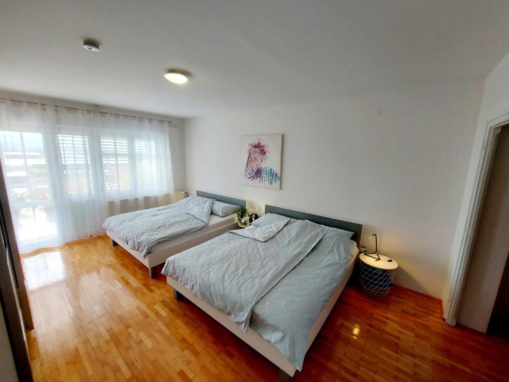 2 letti in una camera con pareti bianche e pavimenti in legno di Accommodation Kolar City center Zabok a Zabok