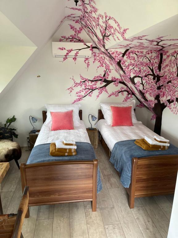 twee bedden in een kamer met een kersenboom muurschildering bij B&B Bijzonder in Drachten