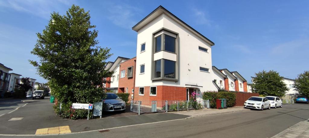 una casa bianca e rossa su una strada con un albero di Arena House a Manchester