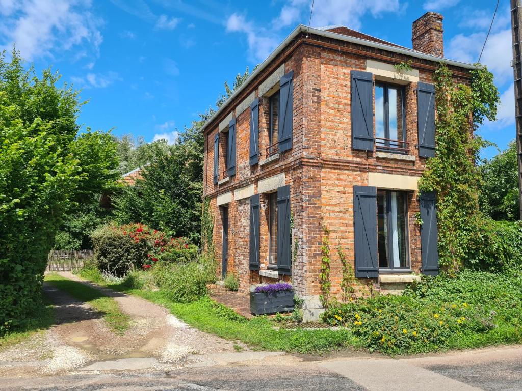 ein altes Backsteinhaus mit schwarzen Fenstern auf einer Straße in der Unterkunft Maison La Cigogne Noire in La Loge-aux-Chèvres