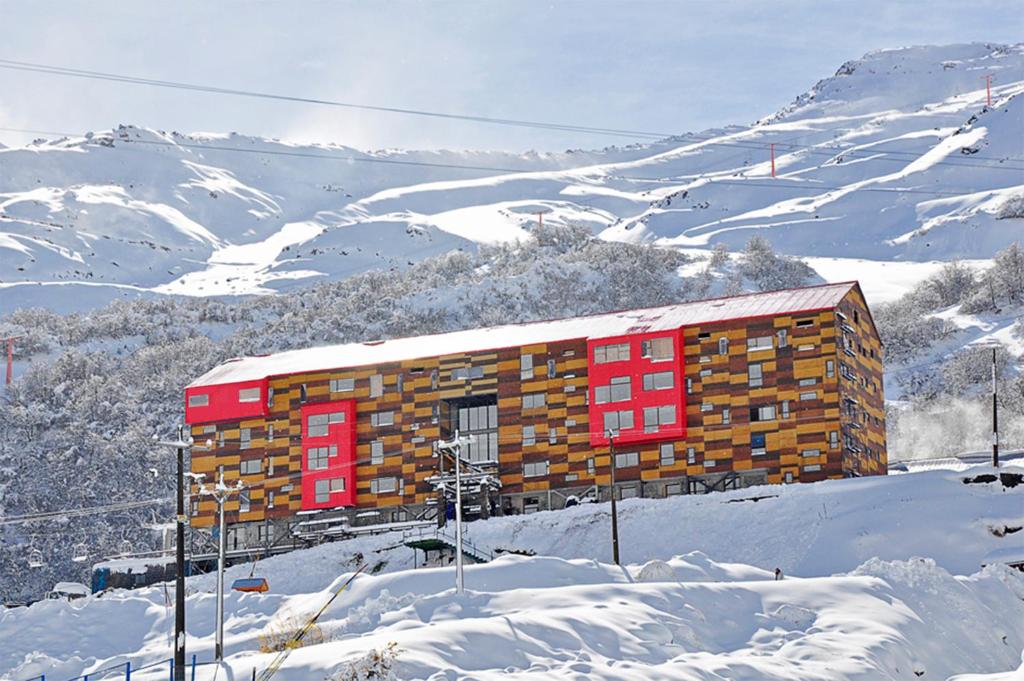 um edifício ao lado de uma montanha coberta de neve em Hotel Alto Nevados em Nevados de Chillan