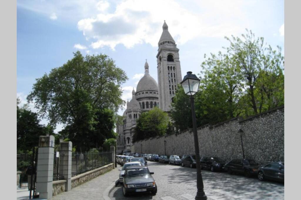 un bâtiment avec des voitures garées dans une rue éclairée dans l'établissement Charming apartment in Montmartre, à Paris