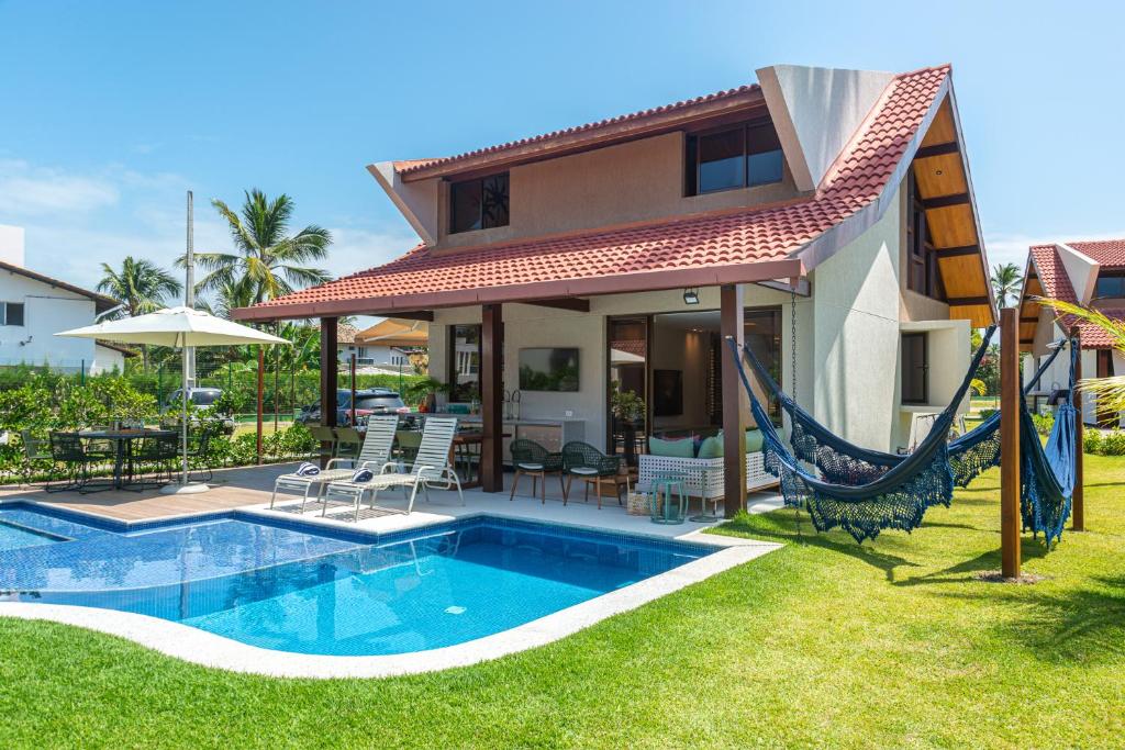 ein Haus mit einem Pool und einer Hängematte im Hof in der Unterkunft Bangalô 57 Oka in Porto De Galinhas