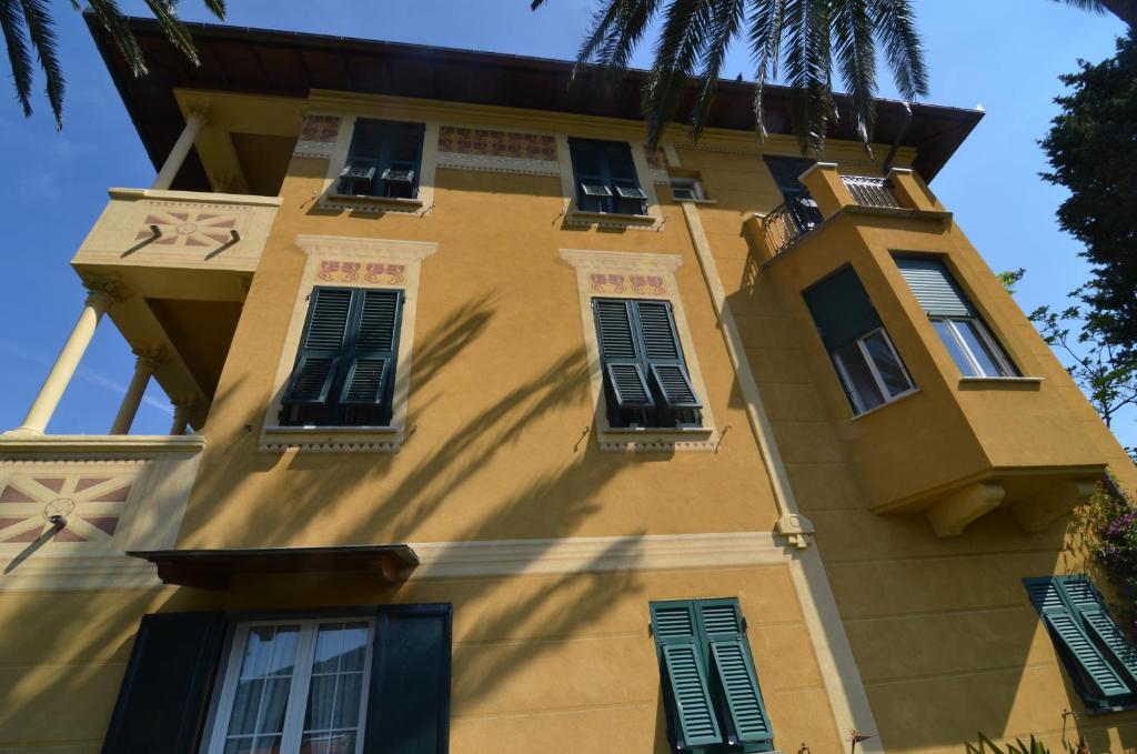 a yellow building with green shutters on it at Villa Margherita in Levanto