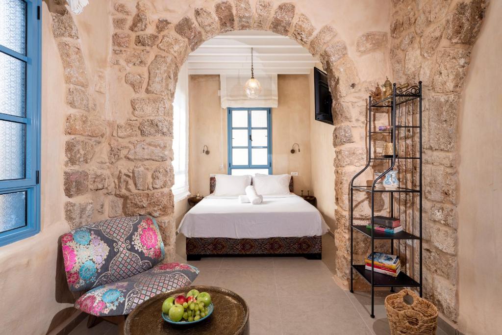 a bedroom with a bed and a chair and a table at Arabesque House in ‘Akko