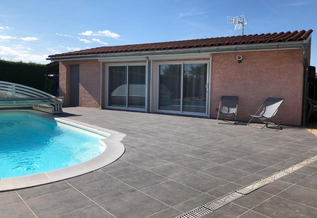 a patio with two chairs next to a swimming pool at Chambres d'Hôtes Chez Florence in Montmerle Sur Saône