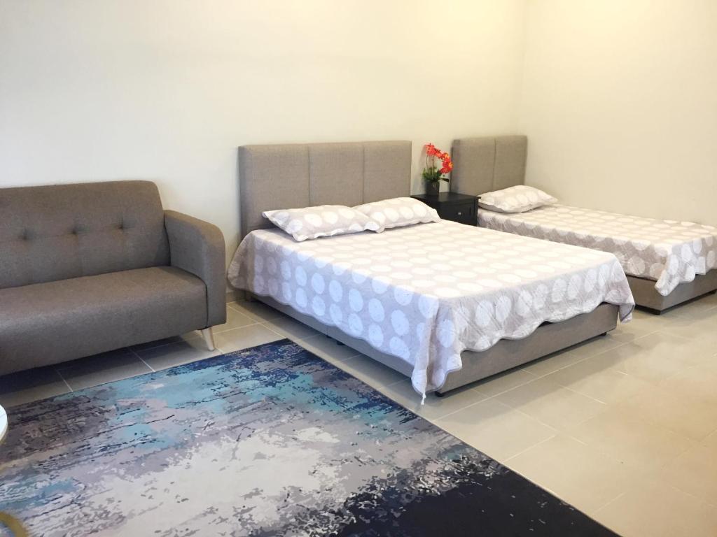 a bedroom with two beds and a couch and a rug at CASA ADELIA STUDIO CHUKAI KEMAMAN in Cukai