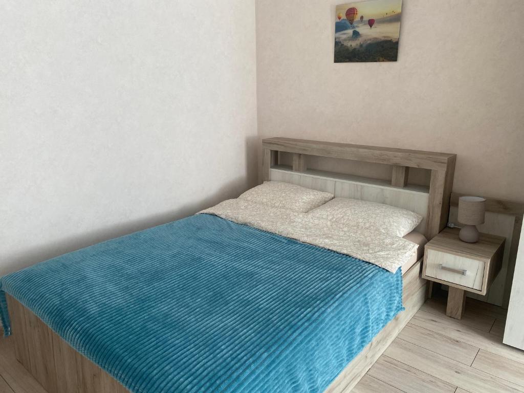 a small bedroom with a bed with a blue blanket at Уютные апартаменты на Речном in Tver
