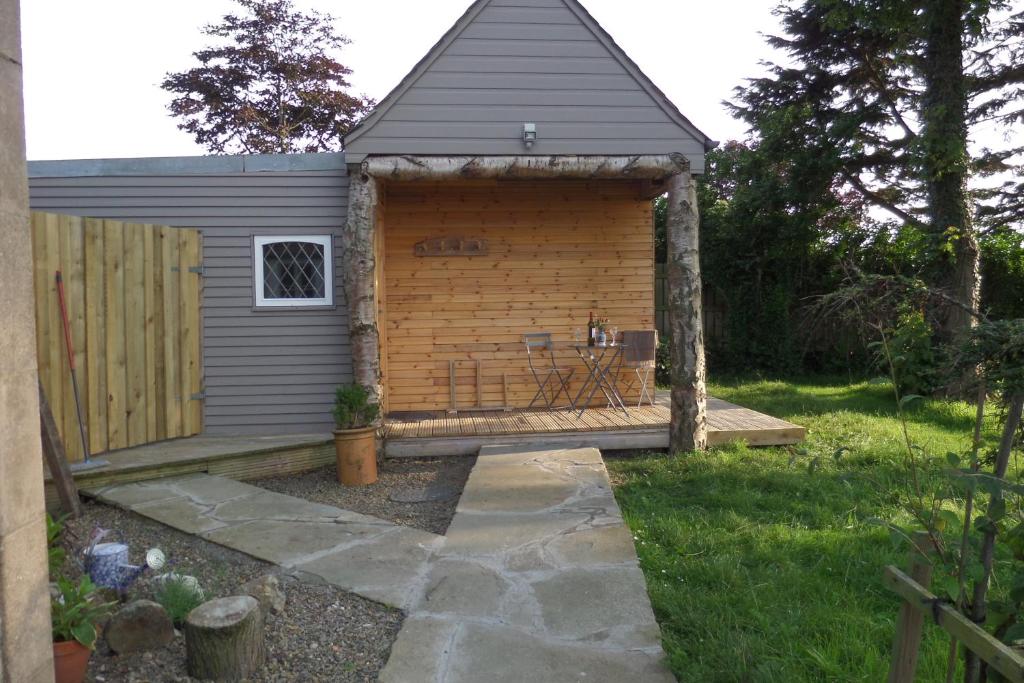 a small shed with a patio in a yard at Charming 1-Bed Garden Lodge in Boyndie Banff in Banff