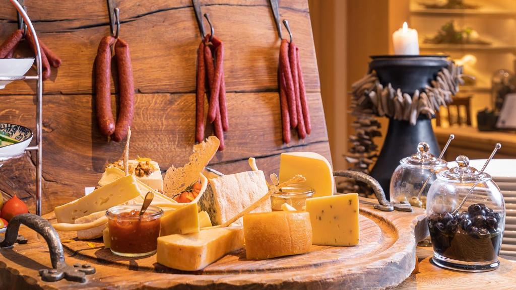 a plate of cheese and sausage on a table at Superior Hotel Tirolerhof - Zell am See in Zell am See