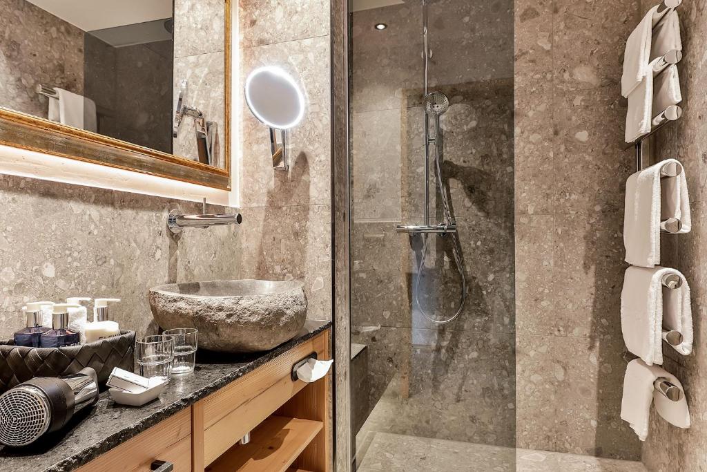 a bathroom with a sink and a glass shower at Superior Hotel Tirolerhof - Zell am See in Zell am See