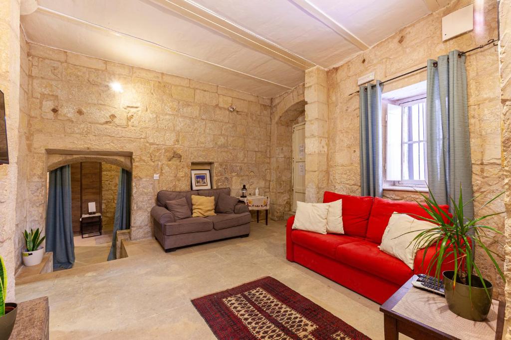 a living room with a red couch and a chair at BRG34 - Historical Vittoriosa Townhouse in Vittoriosa