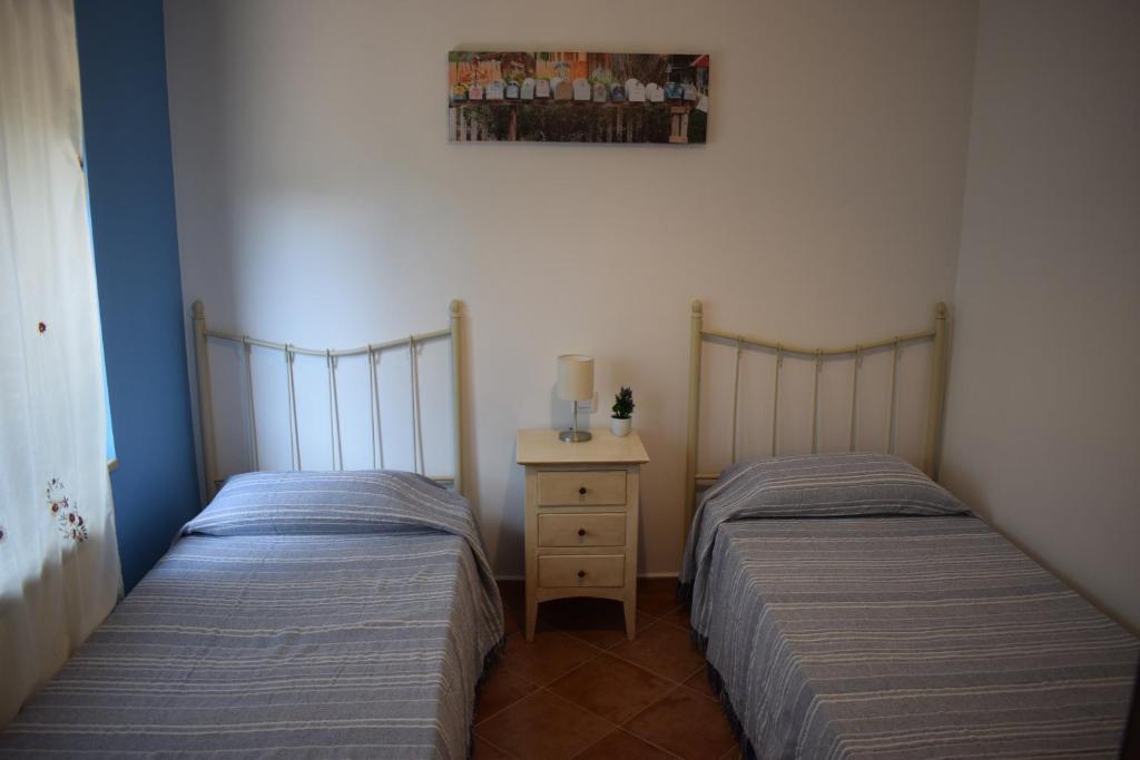 two twin beds in a room with a nightstand and sidx sidx sidx at La Casa del Colmao in Avila