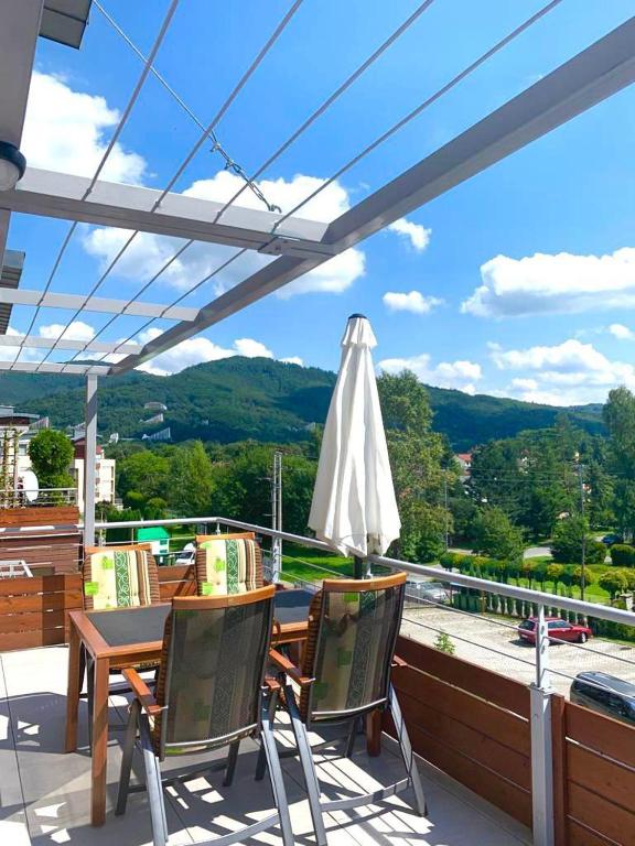 patio ze stołem, krzesłami i parasolem w obiekcie Apartament Panorama Ustronia w Ustroniu