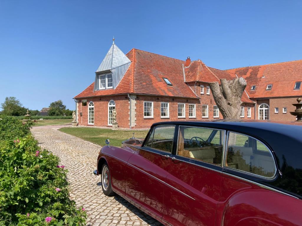 a red car parked in front of a brick house at Account gestört Bitte rufen Sie an Danke in Emmelsbüll-Horsbüll