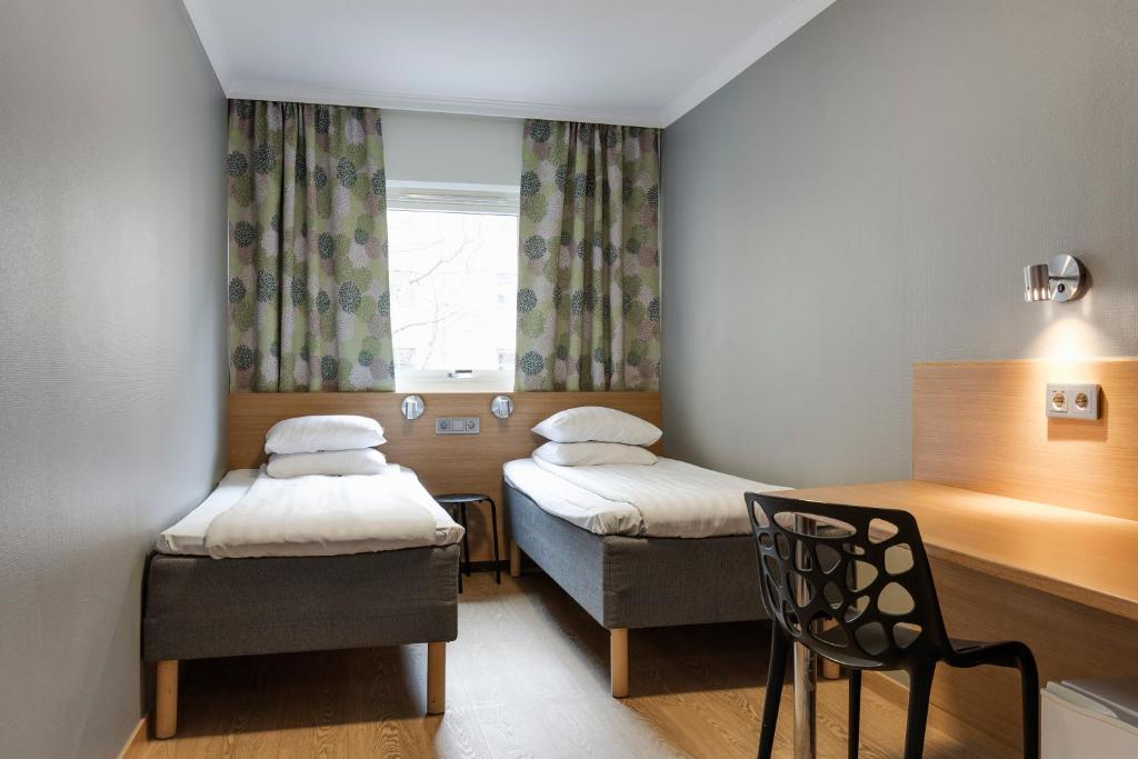 Cette chambre dispose de deux lits, d'une chaise et d'une fenêtre. dans l'établissement Göteborgs Mini-Hotel, à Göteborg