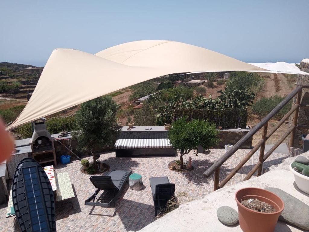 un patio con tavolo e sedie sotto una tenda. di Dammuso Dell`Angelo a Pantelleria