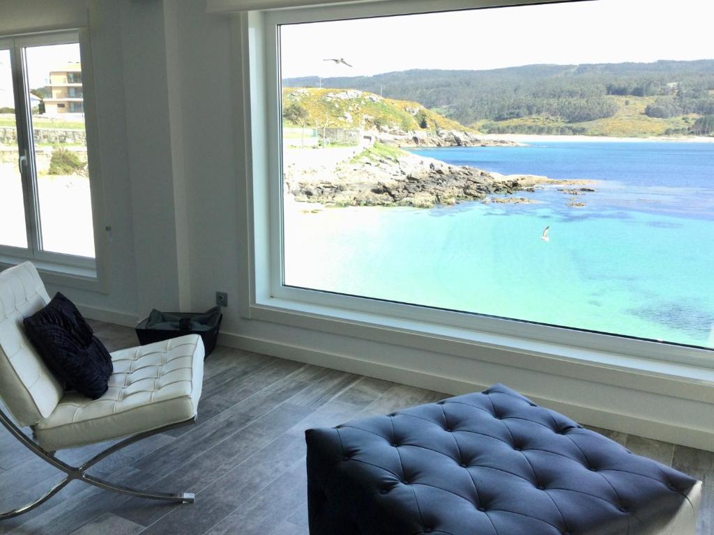 een woonkamer met een groot raam met uitzicht op het strand bij Apartamento Mirador de Corme in Corme-Puerto