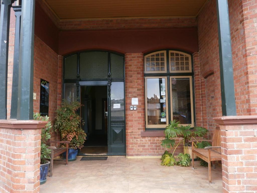 einen Eingang zu einem Backsteingebäude mit Bänken und einer Tür in der Unterkunft Launceston Backpackers in Launceston