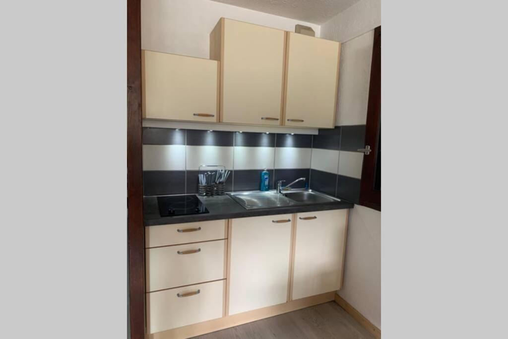 - une cuisine avec des placards blancs et un évier dans l'établissement Superbe appartement avec parking gratuit sur place, à Bourg-Saint-Maurice
