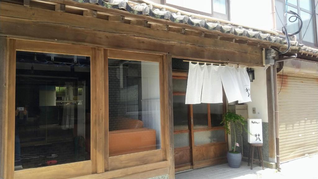 a store front with glass doors and a white shirt hanging at 呼子の港路地の古民家一棟貸切宿梵soyogi in Karatsu