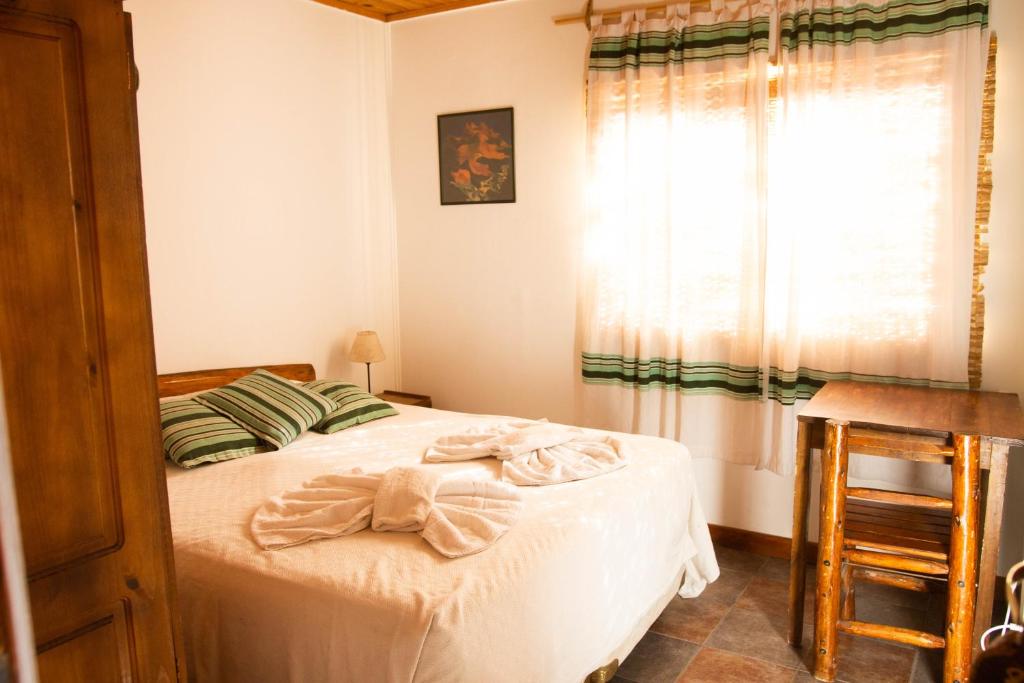 a bedroom with a bed with white sheets and a window at EcoMalargüe Posada & Hostel in Malargüe