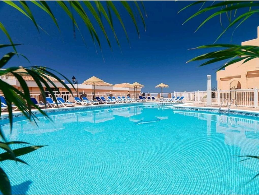 a large swimming pool with chairs and umbrellas at Charming Sunset View Apt Heater Pool Costa Adeje in Adeje