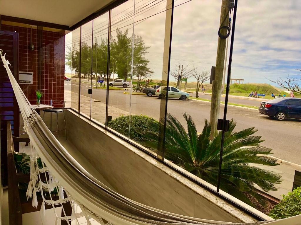 a hammock in front of a building with a window at Apto Beira Mar 3D in Capão da Canoa