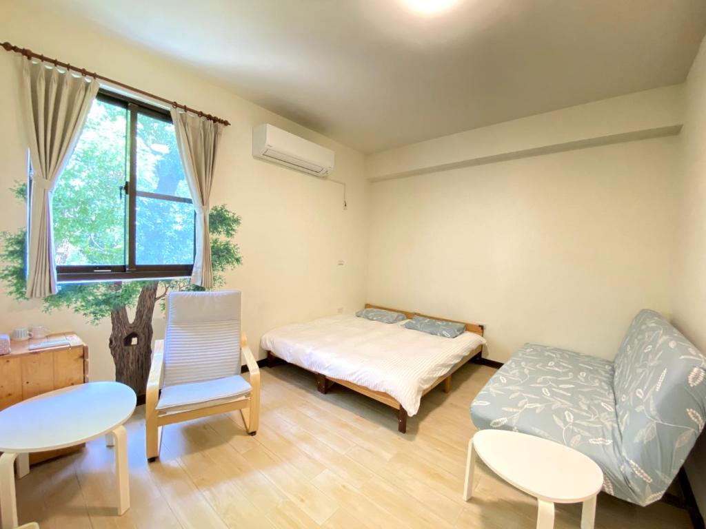 TongluoにあるTree House Café & Homestayのベッド2台、テーブル、椅子が備わる客室です。