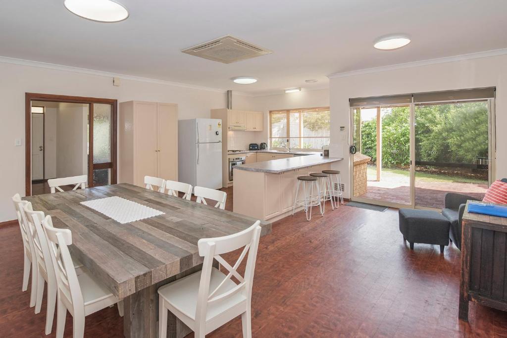 a kitchen and dining room with a wooden table and chairs at Bella Beach House Prevelly 50m from the beach in Prevelly