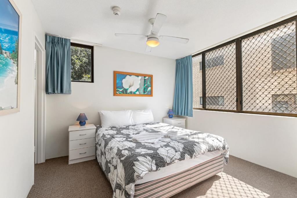 a bedroom with a bed and two windows at Sea Point Ocean Apartments in Caloundra