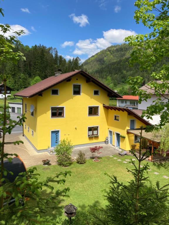 una casa amarilla con una montaña en el fondo en Ferienhaus Elisabeth Selbstversorger Unterkunft, en Sankt Aegyd am Neuwalde
