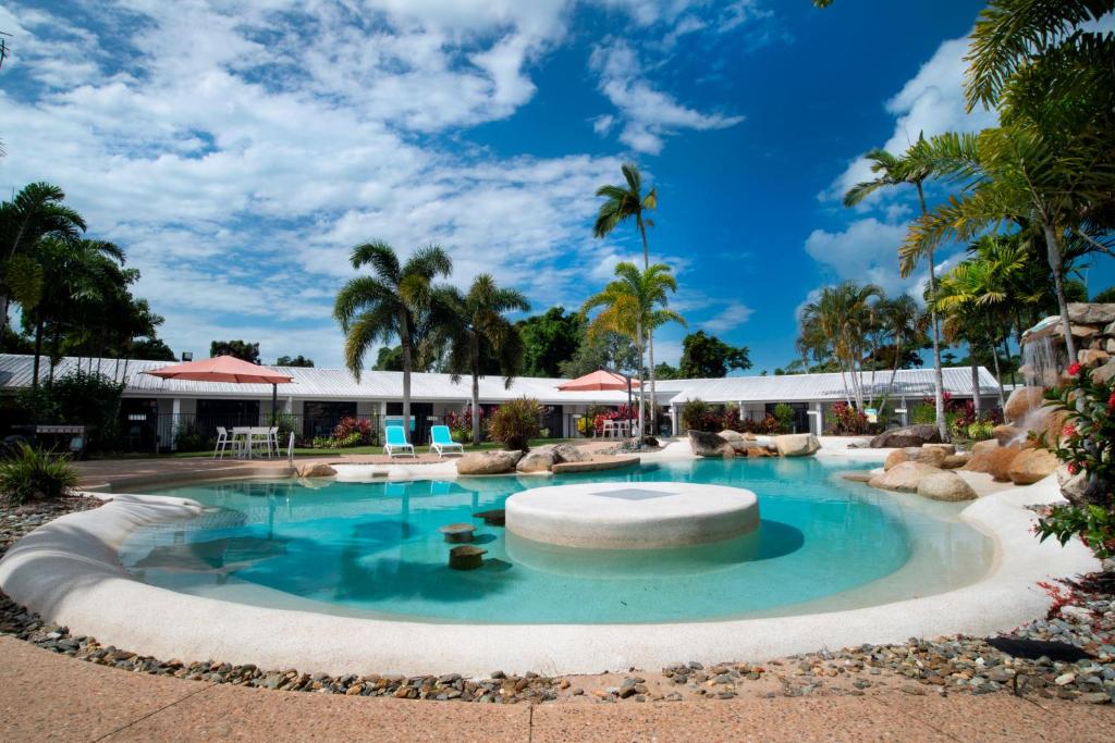 een zwembad in een resort met palmbomen bij Mission Beach Resort in Mission Beach